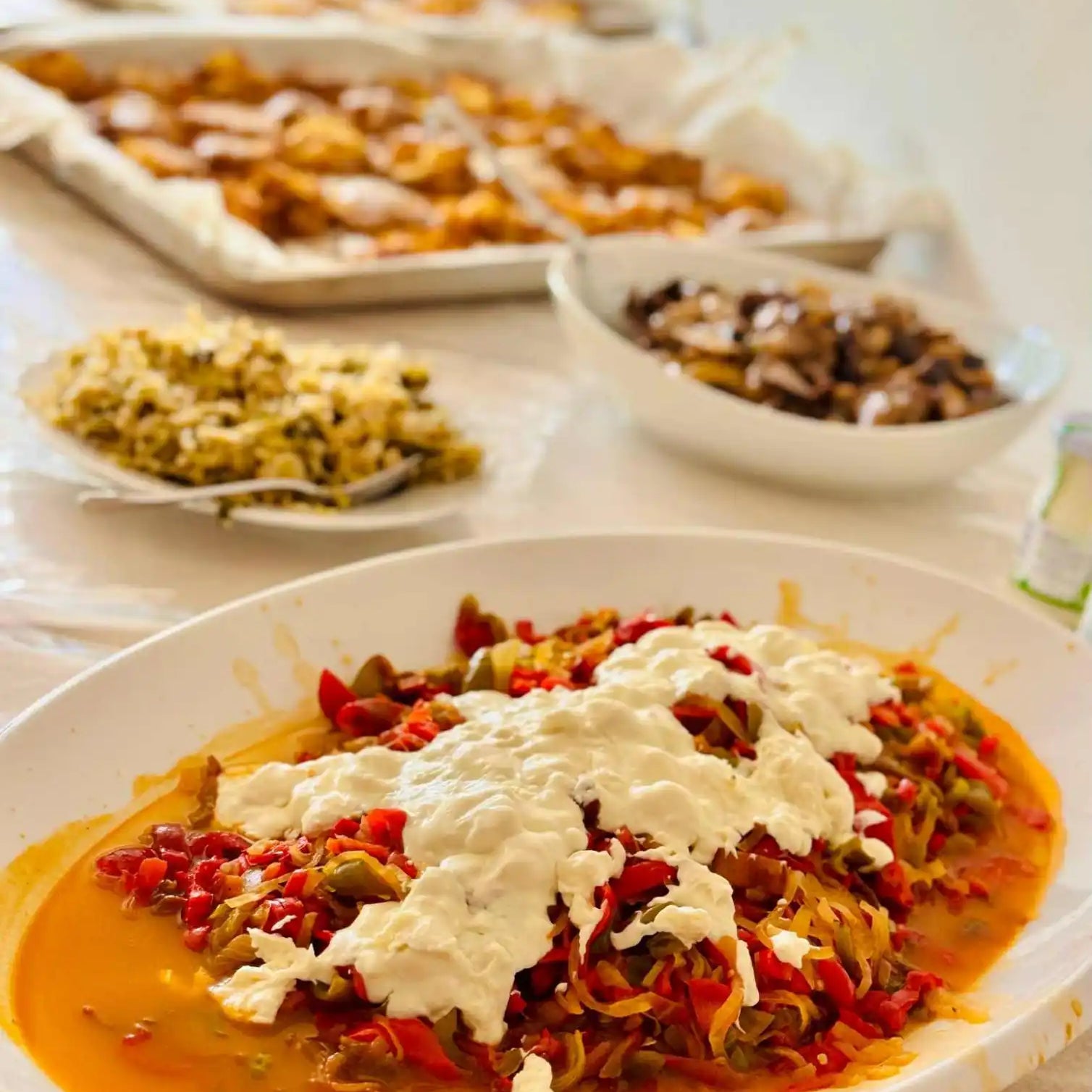 A large platter of stewed peppers with a dollop of fresh cheese.